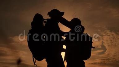 夕阳下幸福的家庭游客剪影拥抱亲吻。团队旅游理念。背着背包的男女情侣